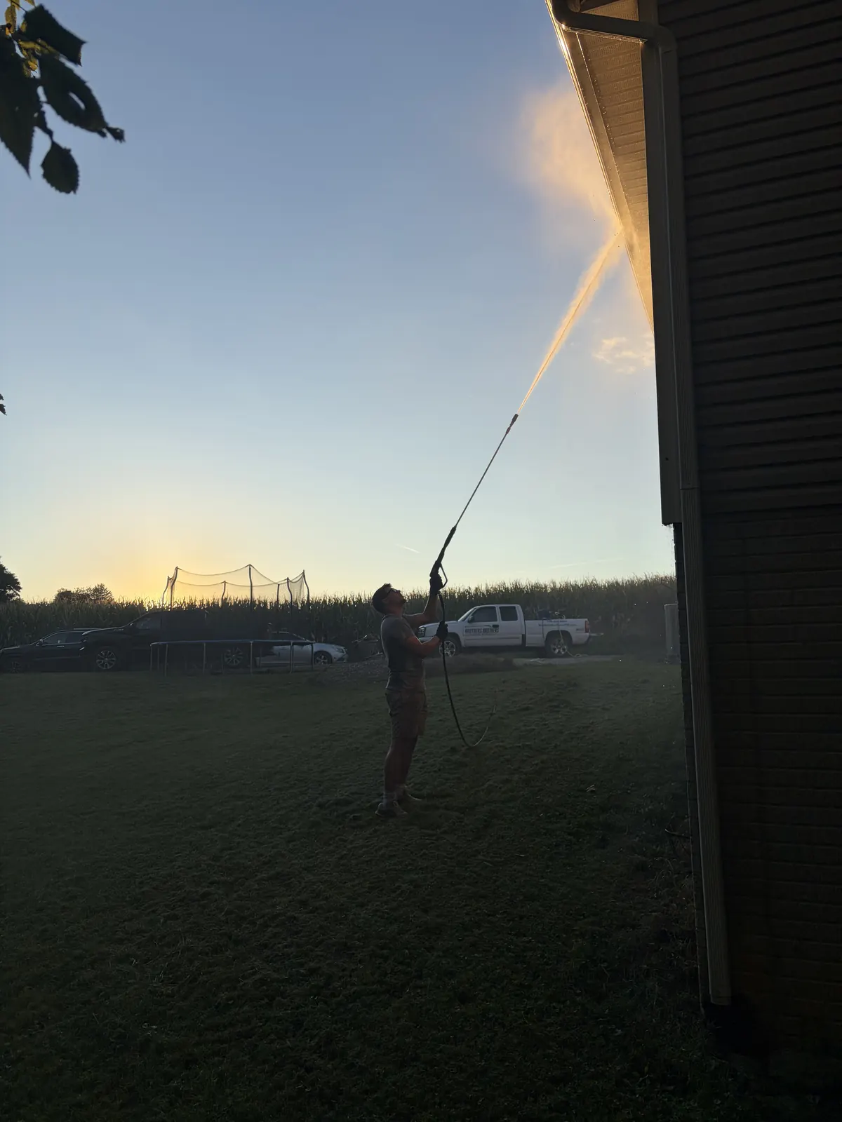 Soft washing a house at sunset with the truck parked in the background
